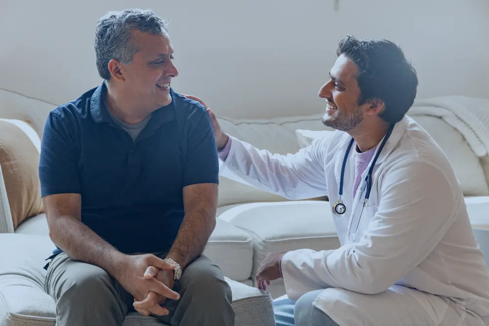Profissional de saúde com a mão no ombro de um paciente durante conversa