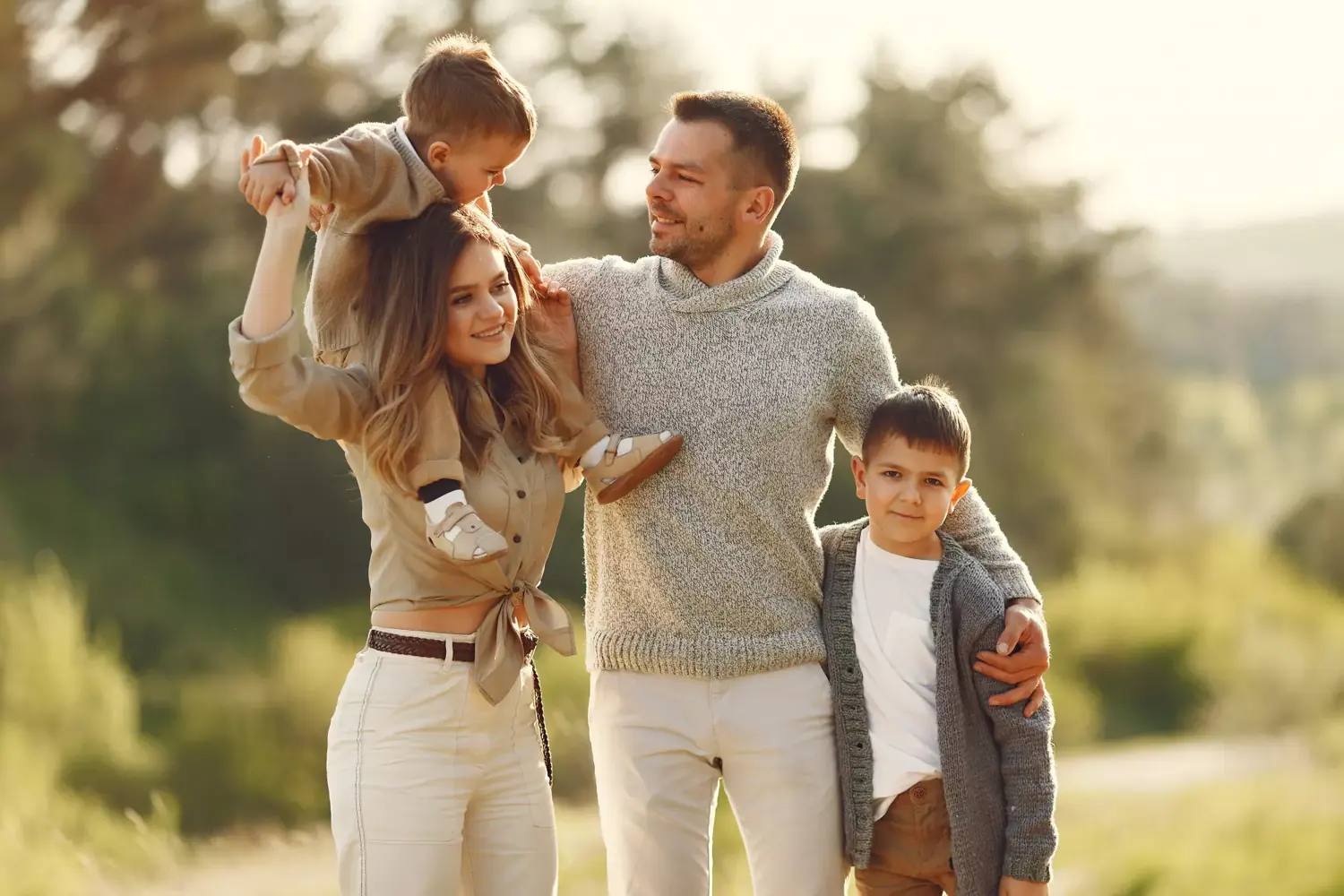 Família reunida ao ar livre, pais e dois filhos sorrindo