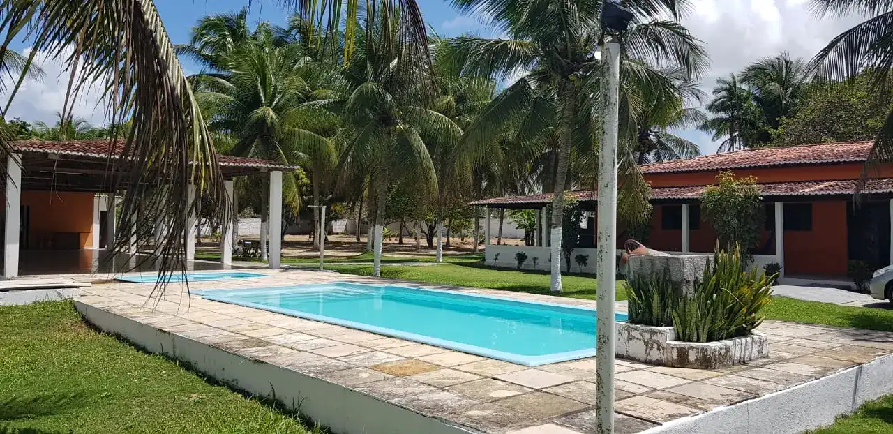 Piscina do Centro de Tratamento Oásis cercada por coqueiros e alojamentos